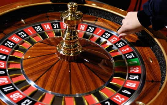 A hand dips onto a spinning. roulette wheel.