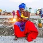 A woman in a brightly colored outfit in Cartagena, Colombia looks at her phone.