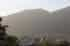 A person in a white t-shirt stands overlooking Caracas, Venezuela, with a hazy mountain in the background.