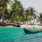 A canoe on the ocean in Panama, with a white sand beach and palm trees in the background.