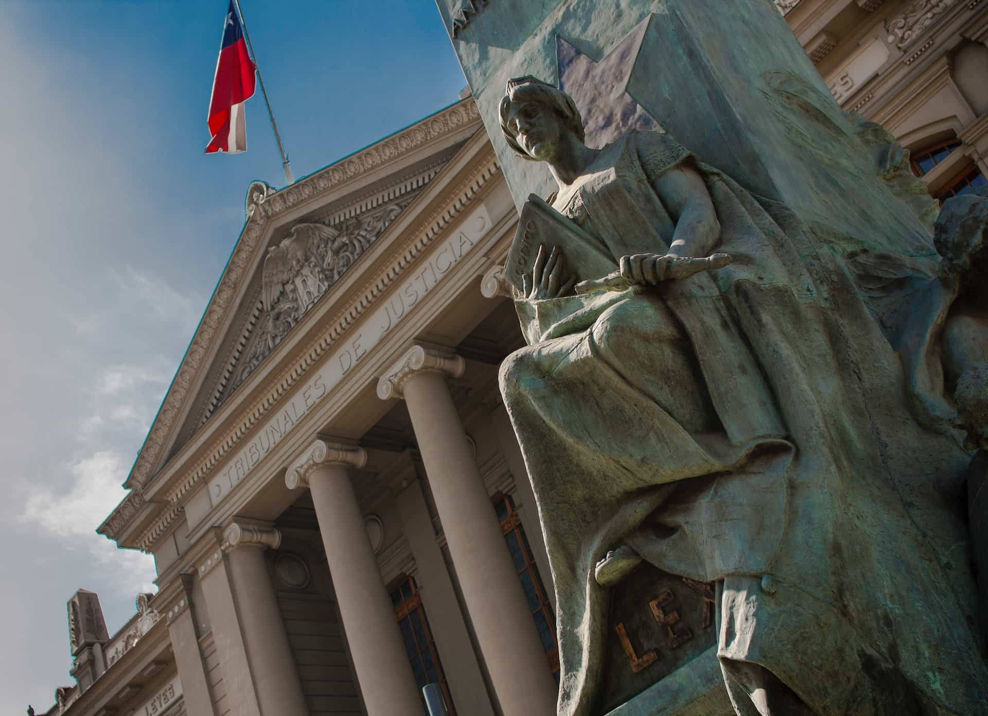 A statue in front of a large government building in Chile, with a facade of columns.