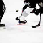 Several hockey players vying for control of the puck on an ice rink during a game of hockey.