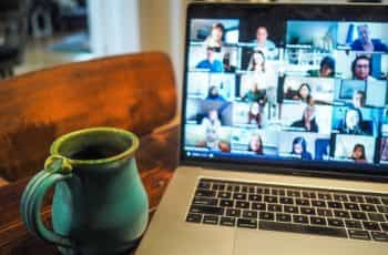 A Macbook displays a group of people on a Zoom call.