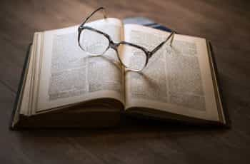 Eyeglasses sit on an open leather-bound book.